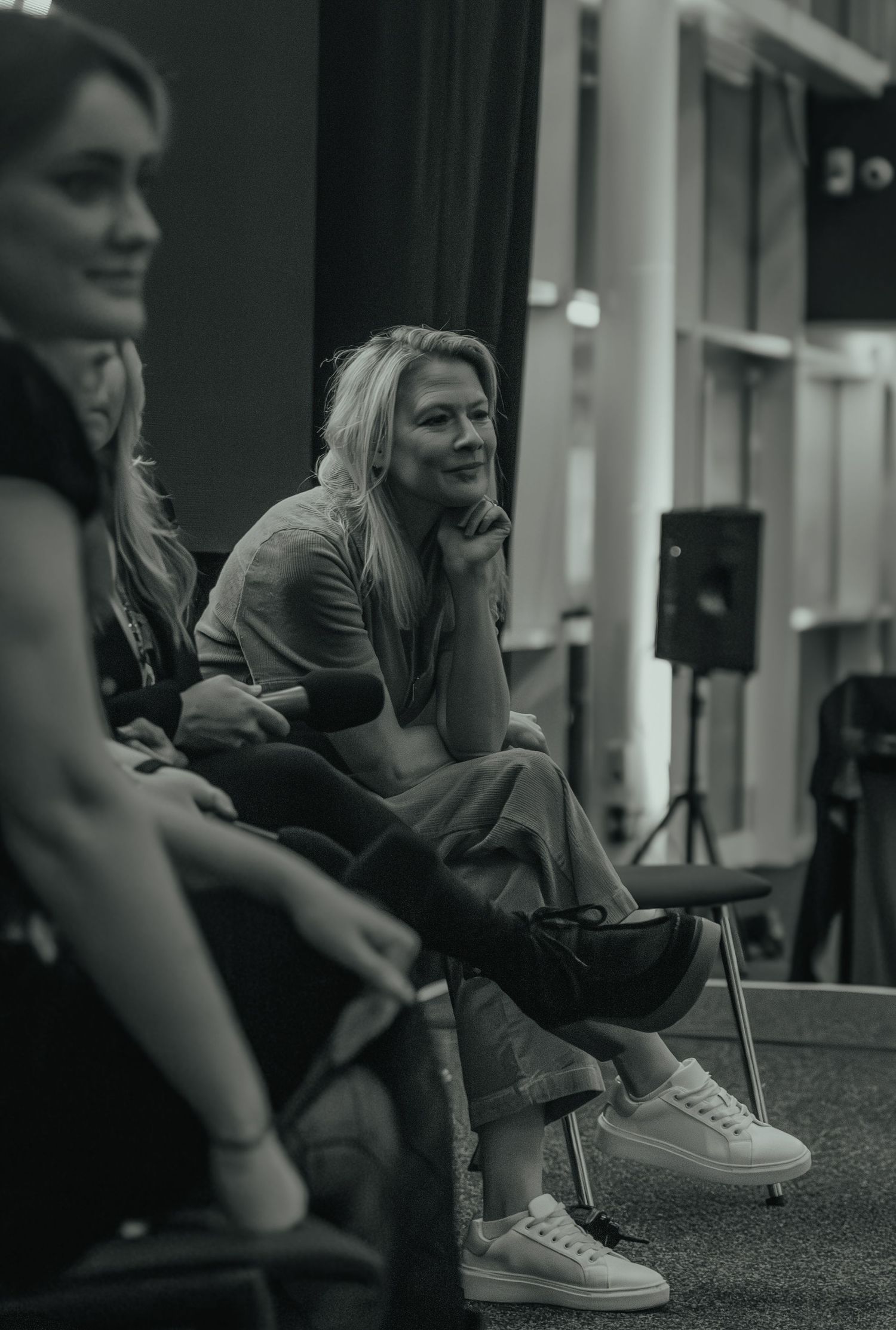Black and white photo of people sitting and chatting at an indoor event.