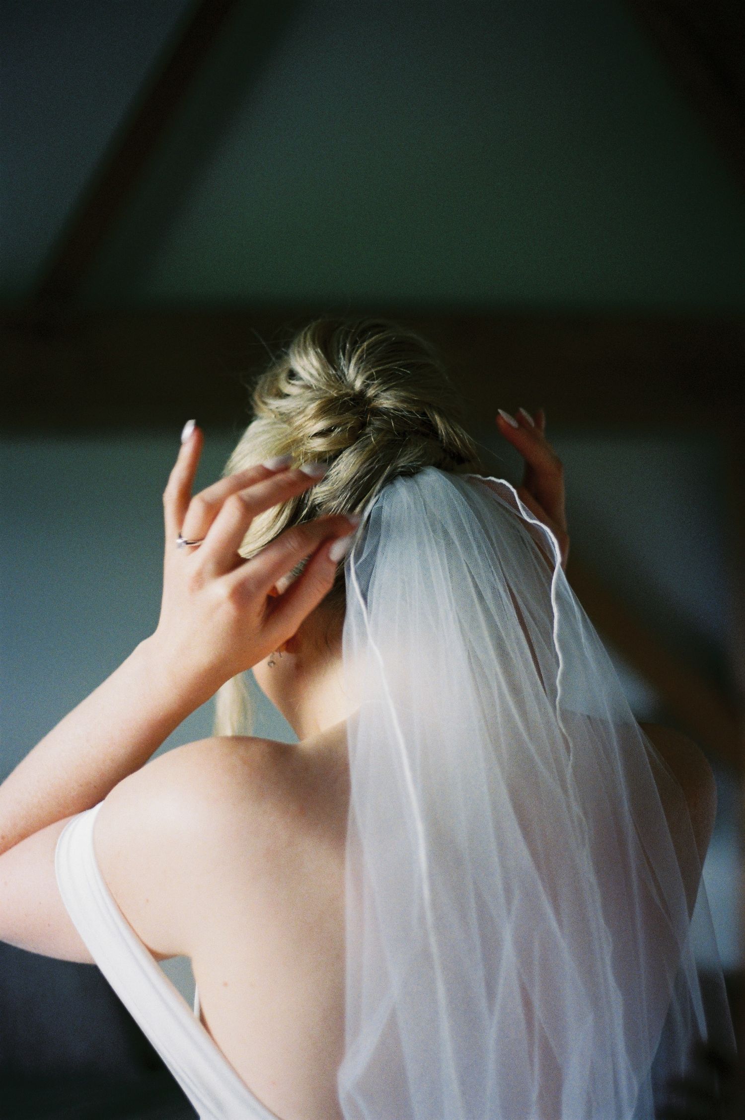 A delicate white bridal veil is being adjusted against a dark background, showing multiple angles of the headpiece.