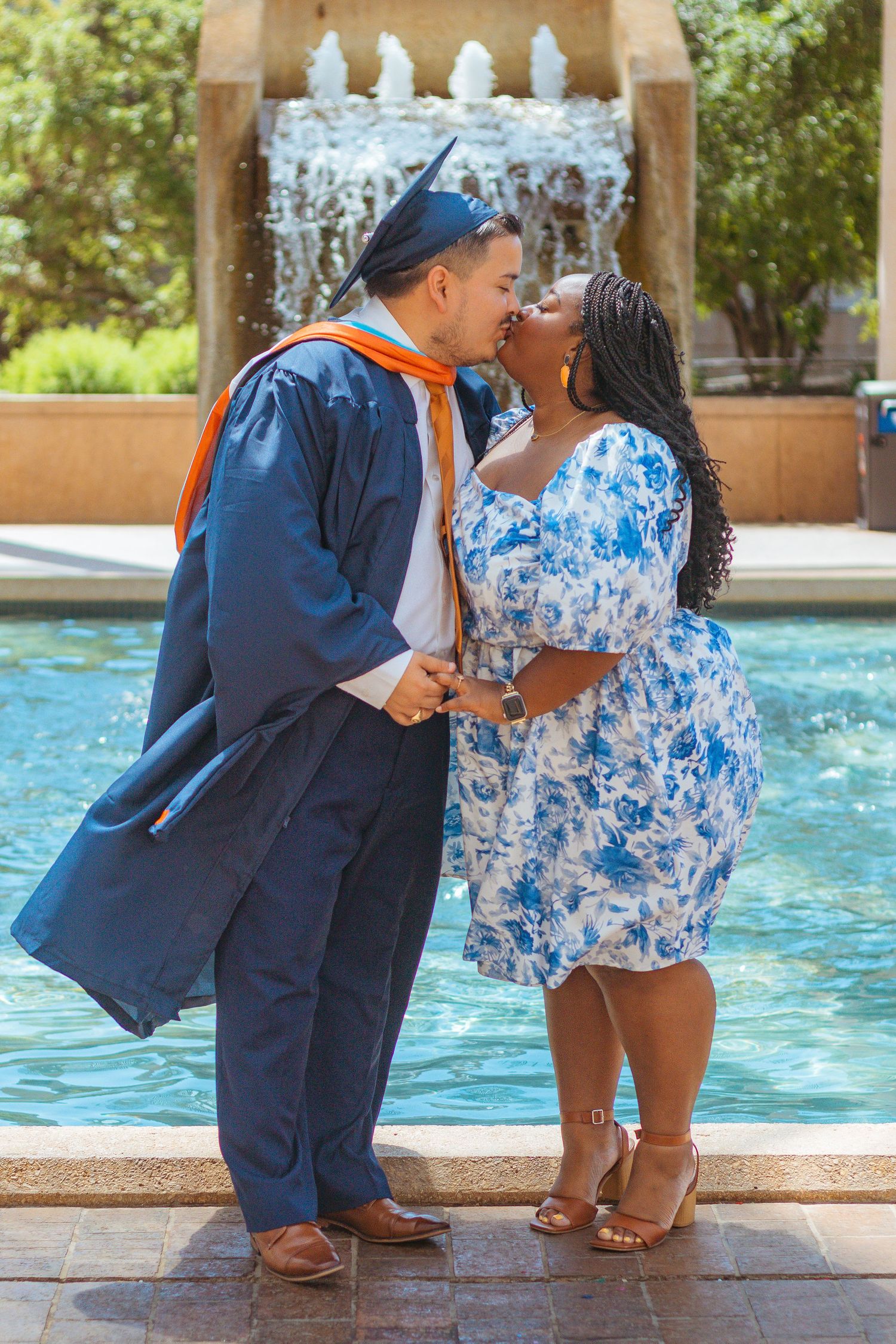 A graduation celebration moment by a fountain with decorative background elements at UTSA.