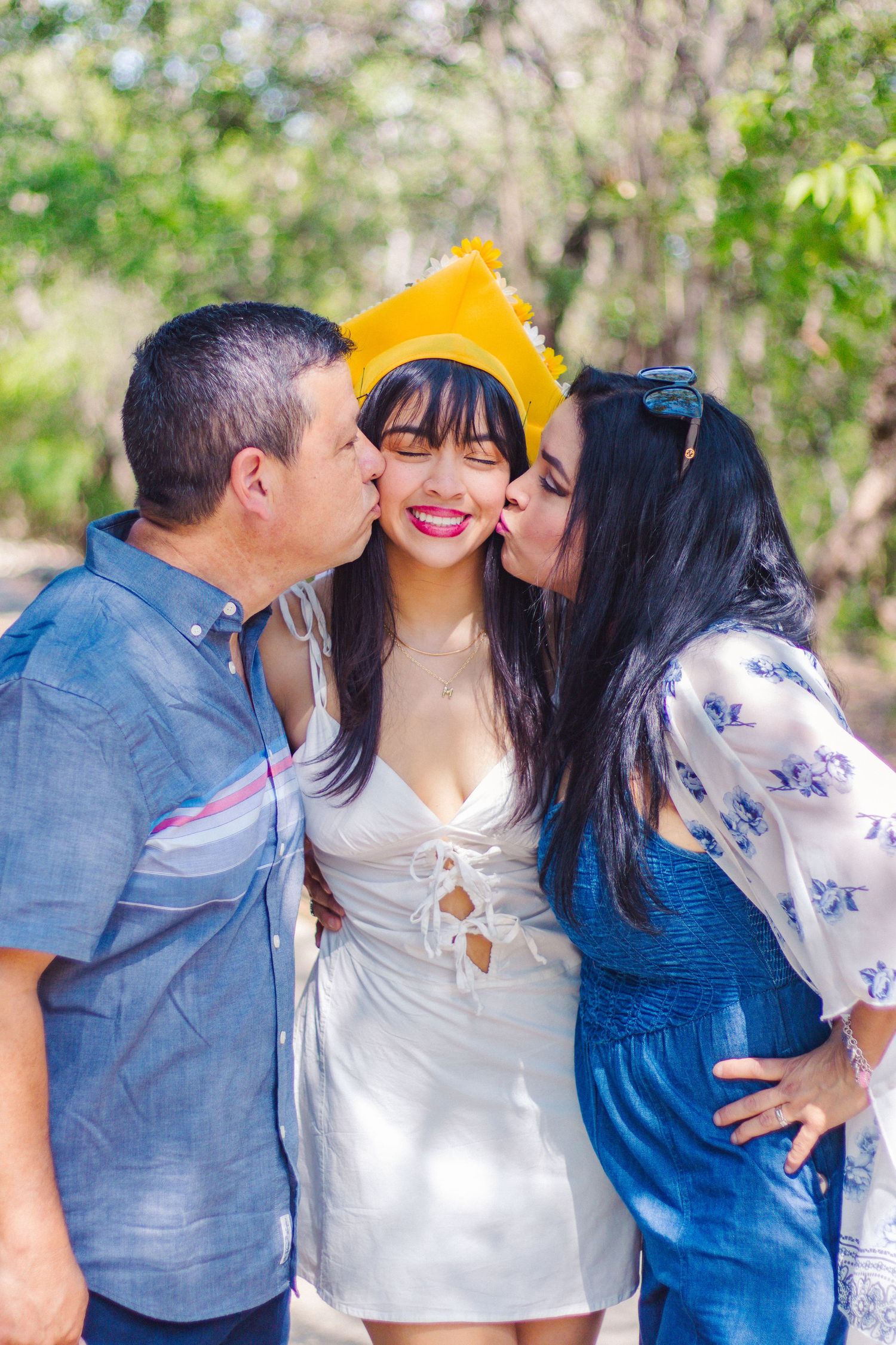 Three people sharing an affectionate moment outdoors with yellow crown accessory at the Japanese Tea Gardens in San Antonio, Texas