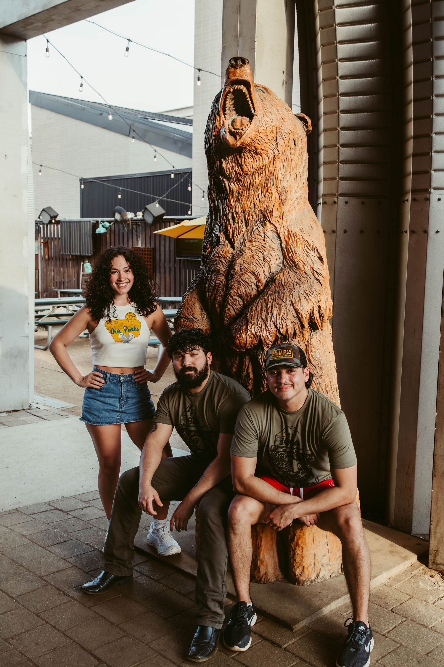 Three bartenders at Camp 1604 in San Antonio, Texas advertising their spring 2025 merch