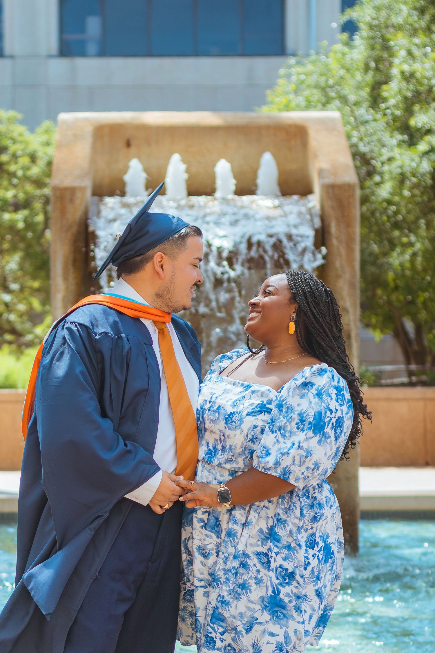 Couple celebrates graduation in formal attire by decorative fountain at UTSA.