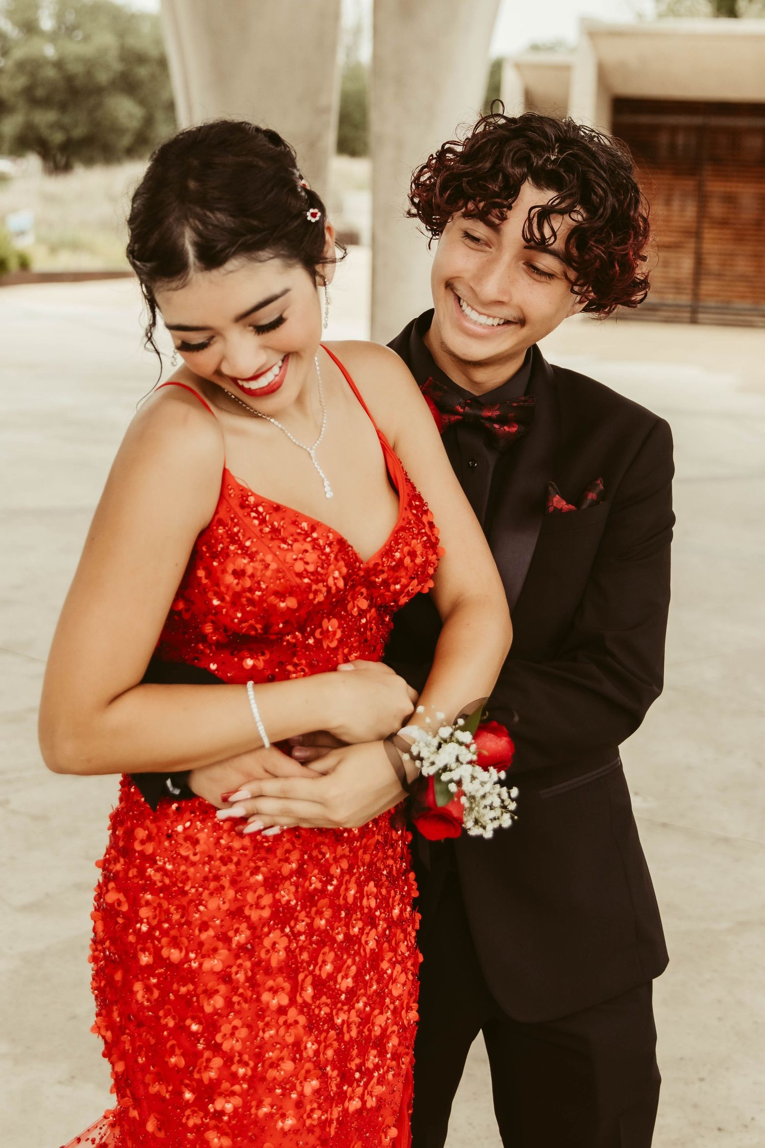 A couple shares a joyful moment in formal wear, with her in a striking red sequined dress.