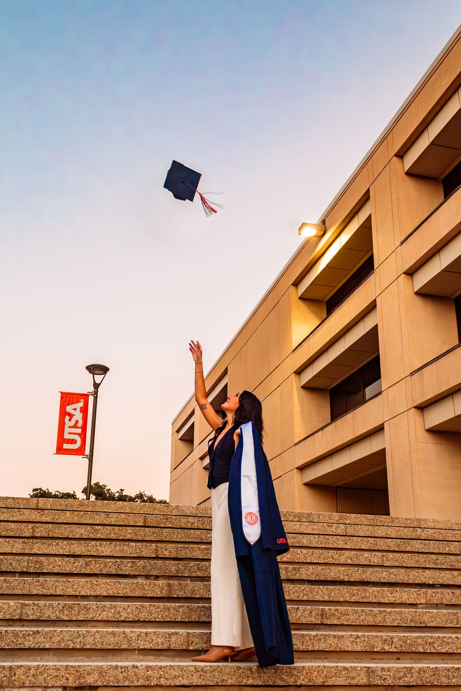 A female portrait on the steps of the University of Texas at San Antonio for a graduation photoshoot