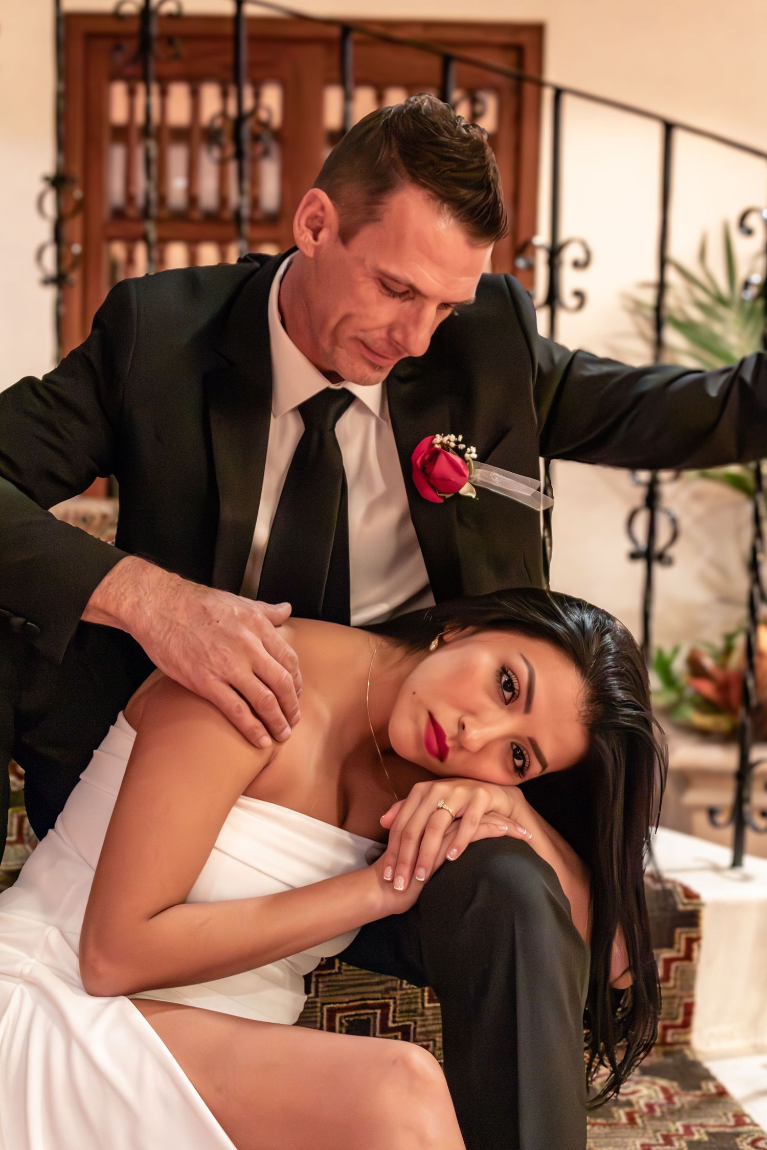 A couple in wedding attire shares an intimate moment on decorative stairs.