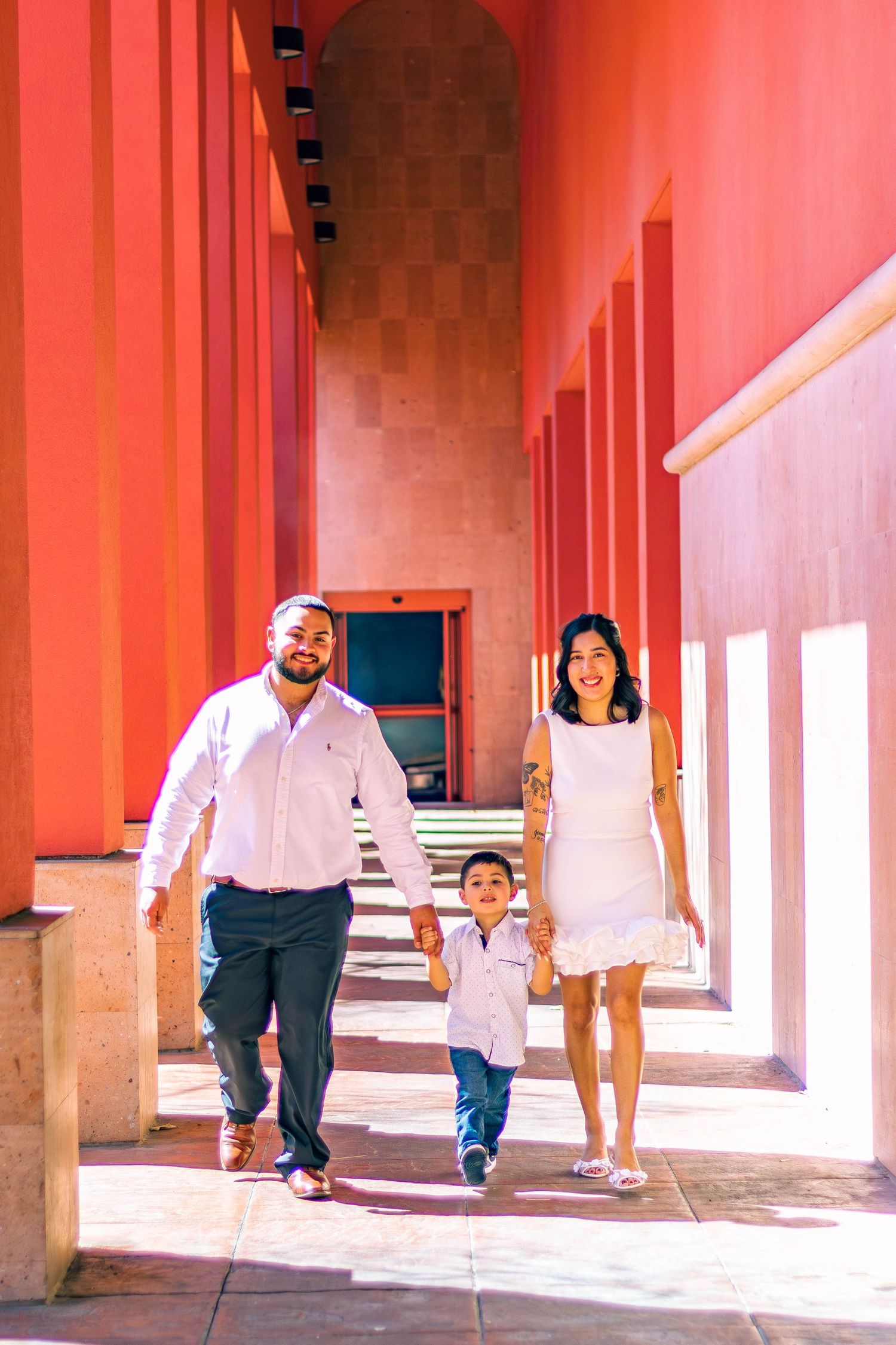 Family walking together down a pink-colored hallway with arched architecture in downtown San Antonio, Texas.