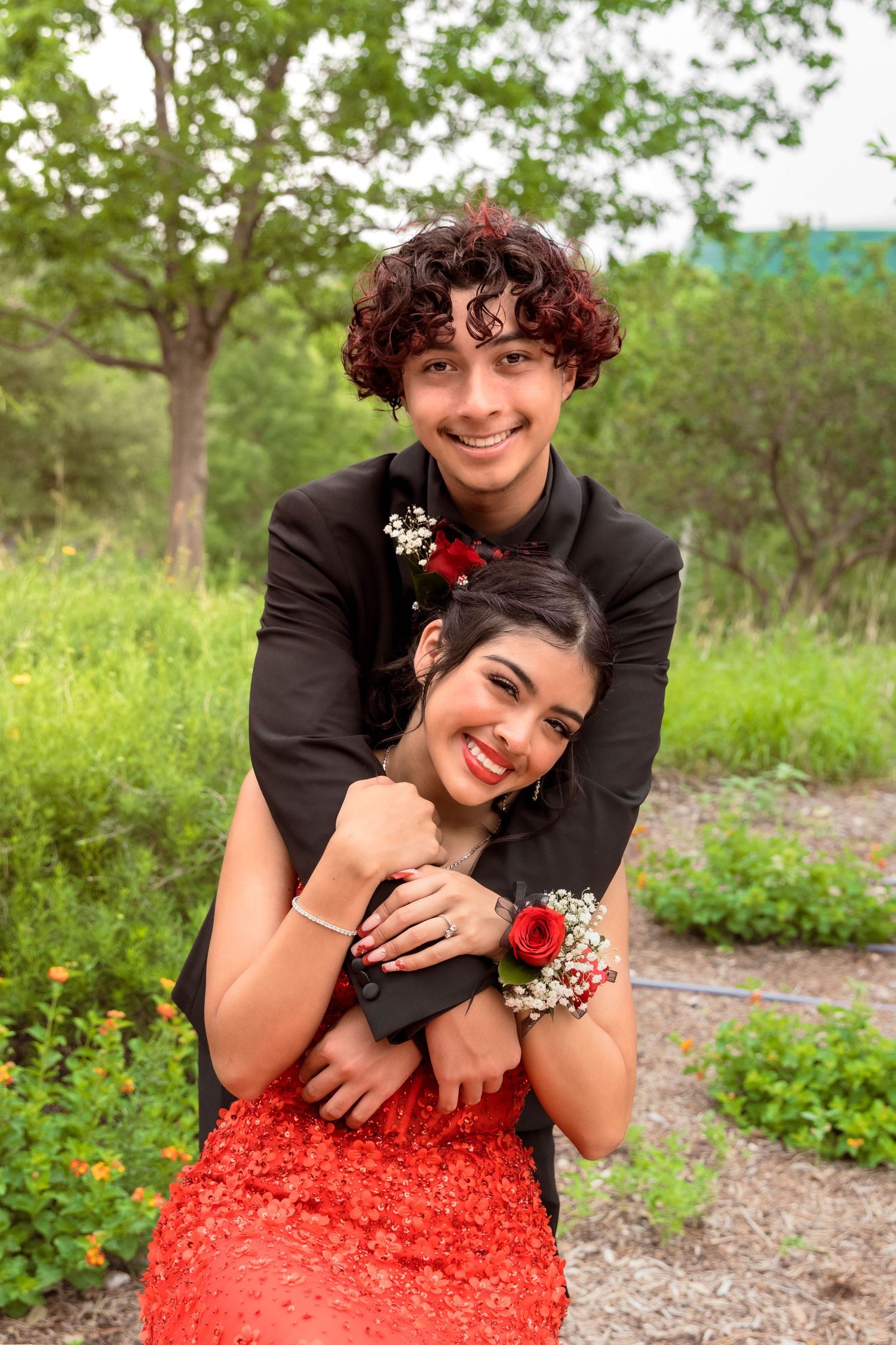 A joyful embrace between a couple in formal wear on a garden path with baby's breath flowers.
