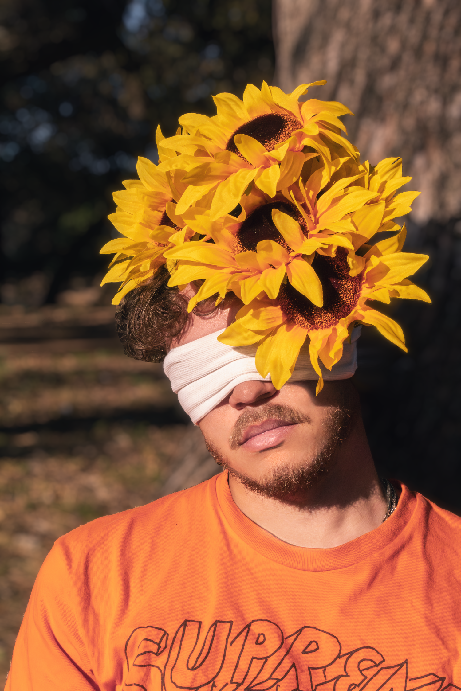 A creative portrait of someone wearing an orange shirt with sunflowers covering their face.