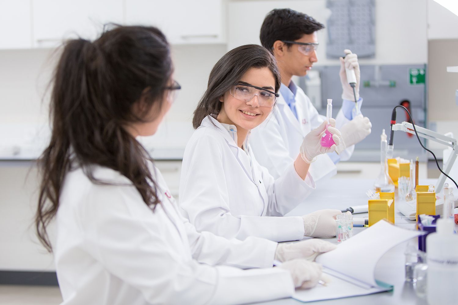 Scientists in white lab coats examine samples in a modern laboratory while conducting research experiments.
