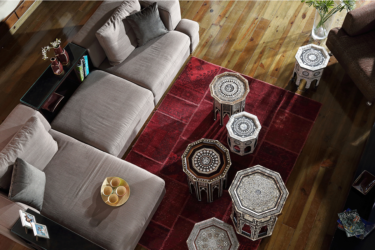 Overhead view of a modern living room with gray sectional sofa and circular patterns on a red area rug.