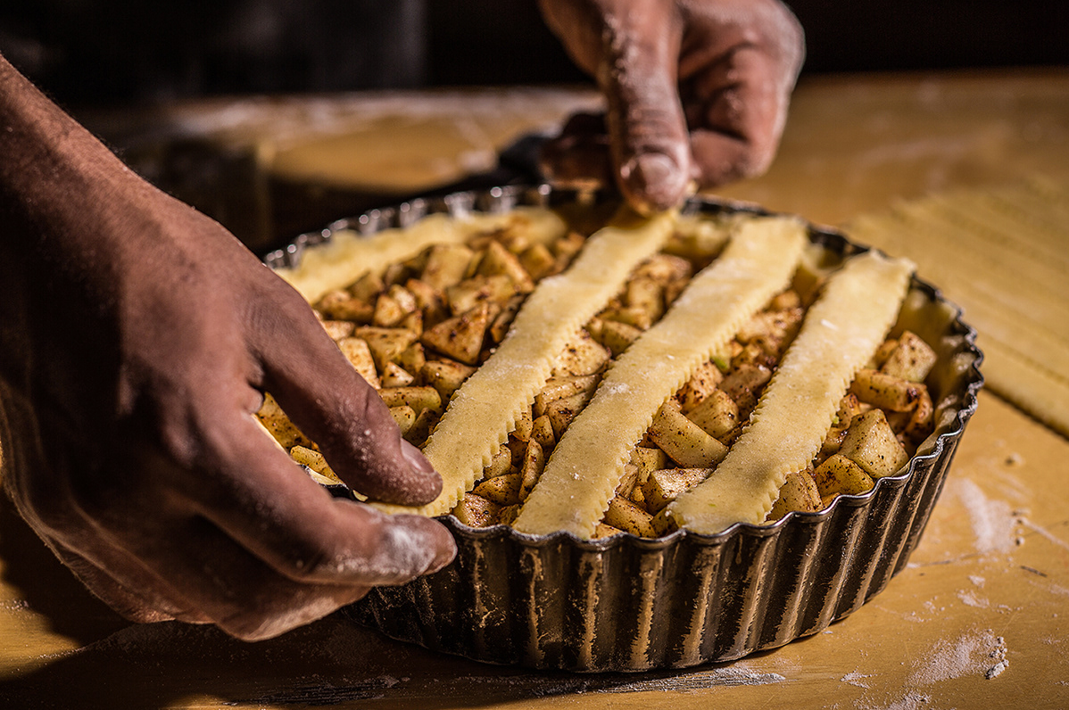 Preparation of apple pie with lattice crust pattern being assembled in a tart pan.