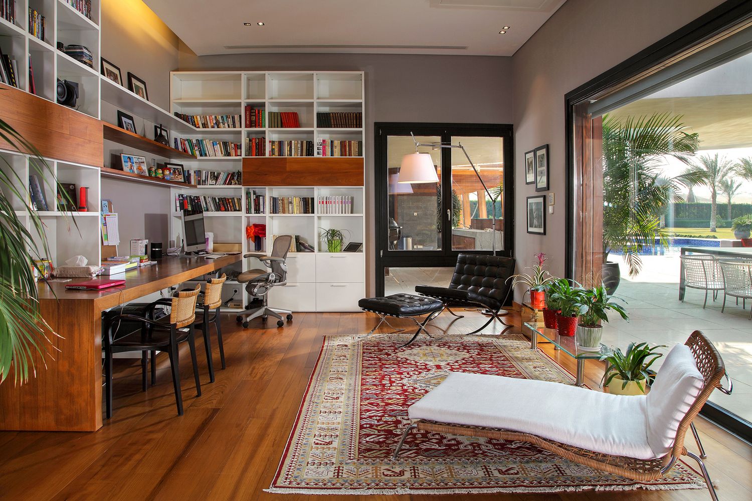 Modern home office with built-in bookshelves, wooden floors and oriental rug.