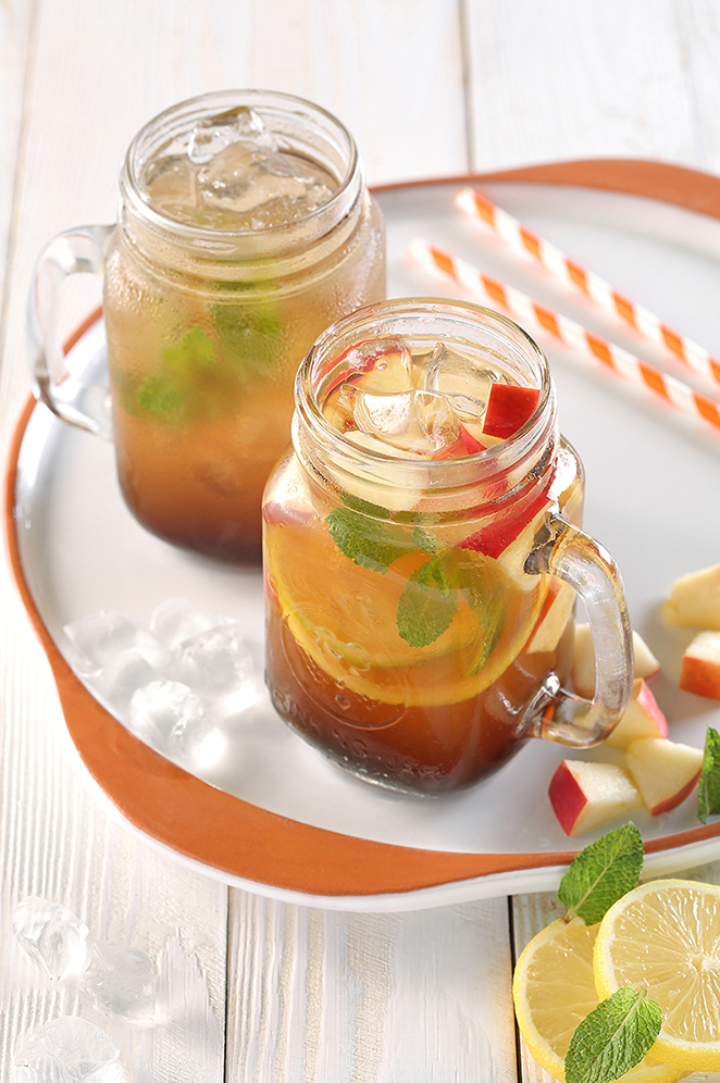 Refreshing iced tea with citrus slices and mint in mason jar glasses with striped straws.