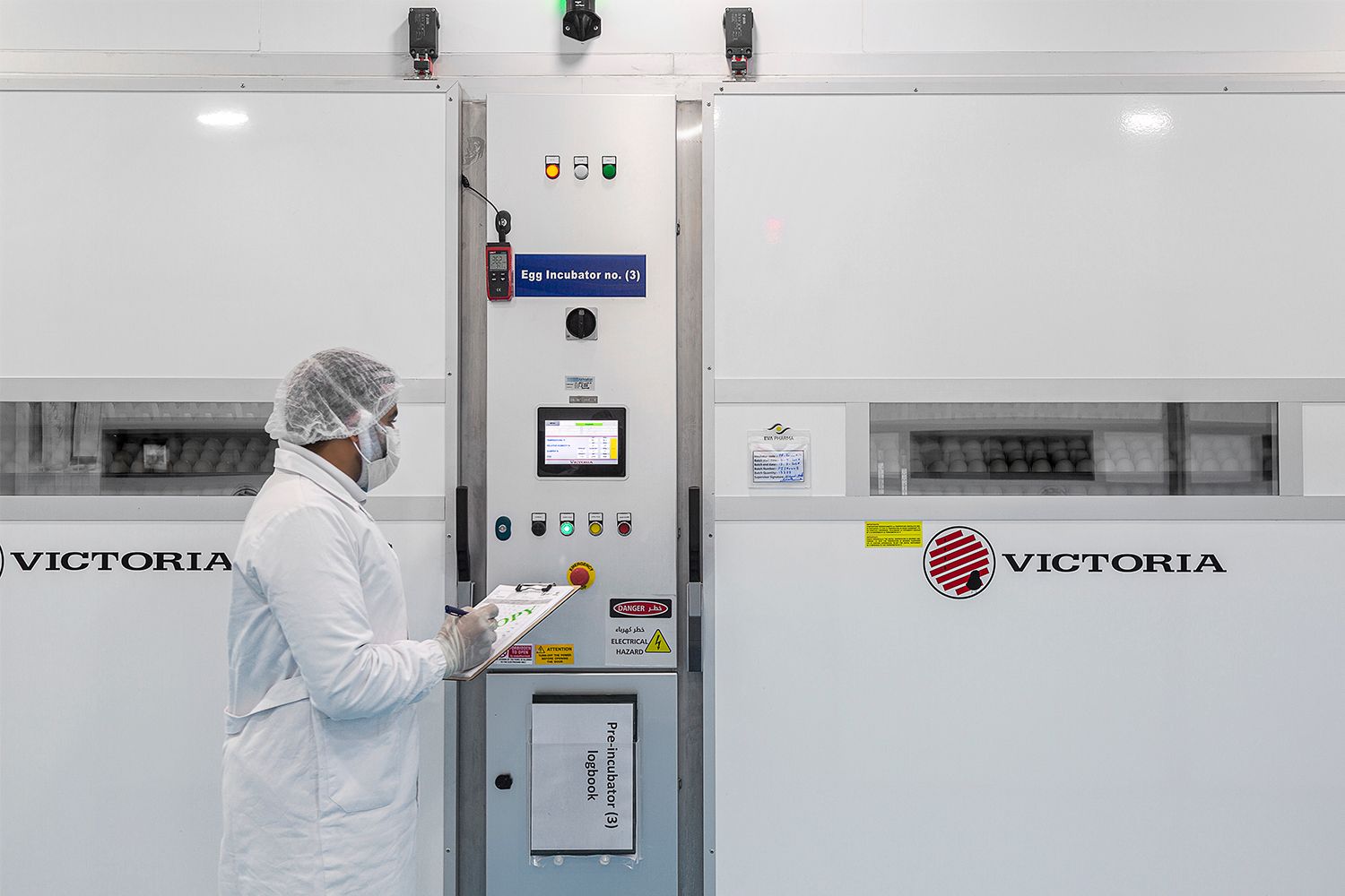 Clean room technician monitoring control panel of industrial pharmaceutical equipment.