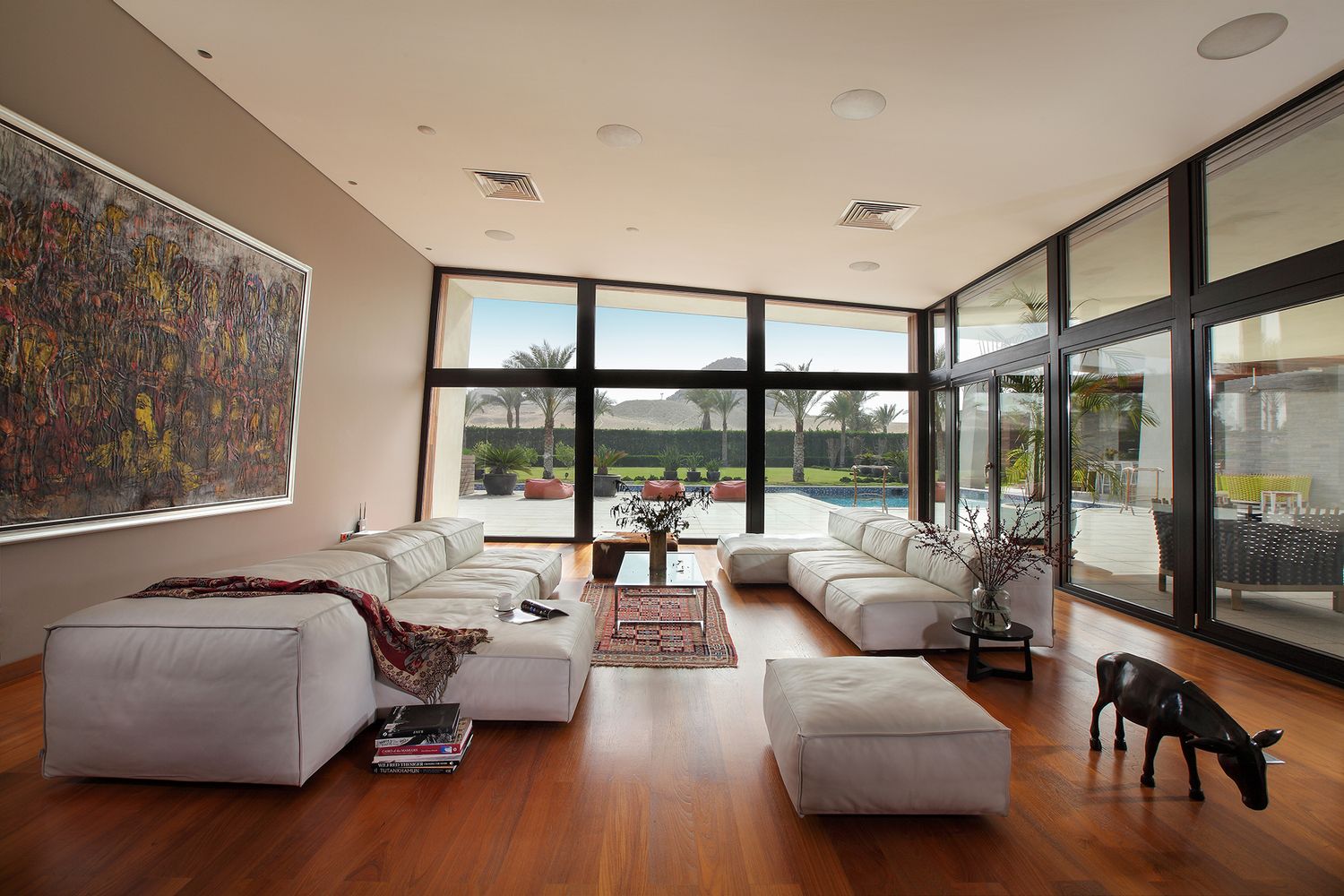 Spacious living room with white sectional sofa, hardwood floors and floor-to-ceiling windows.