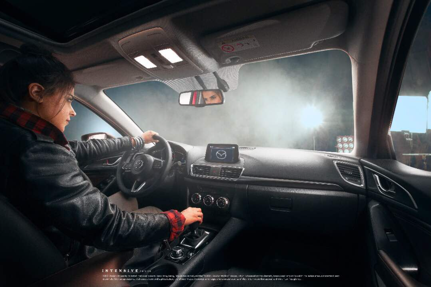 Interior view of modern car dashboard and steering wheel during daytime drive. Mazda 3 ad