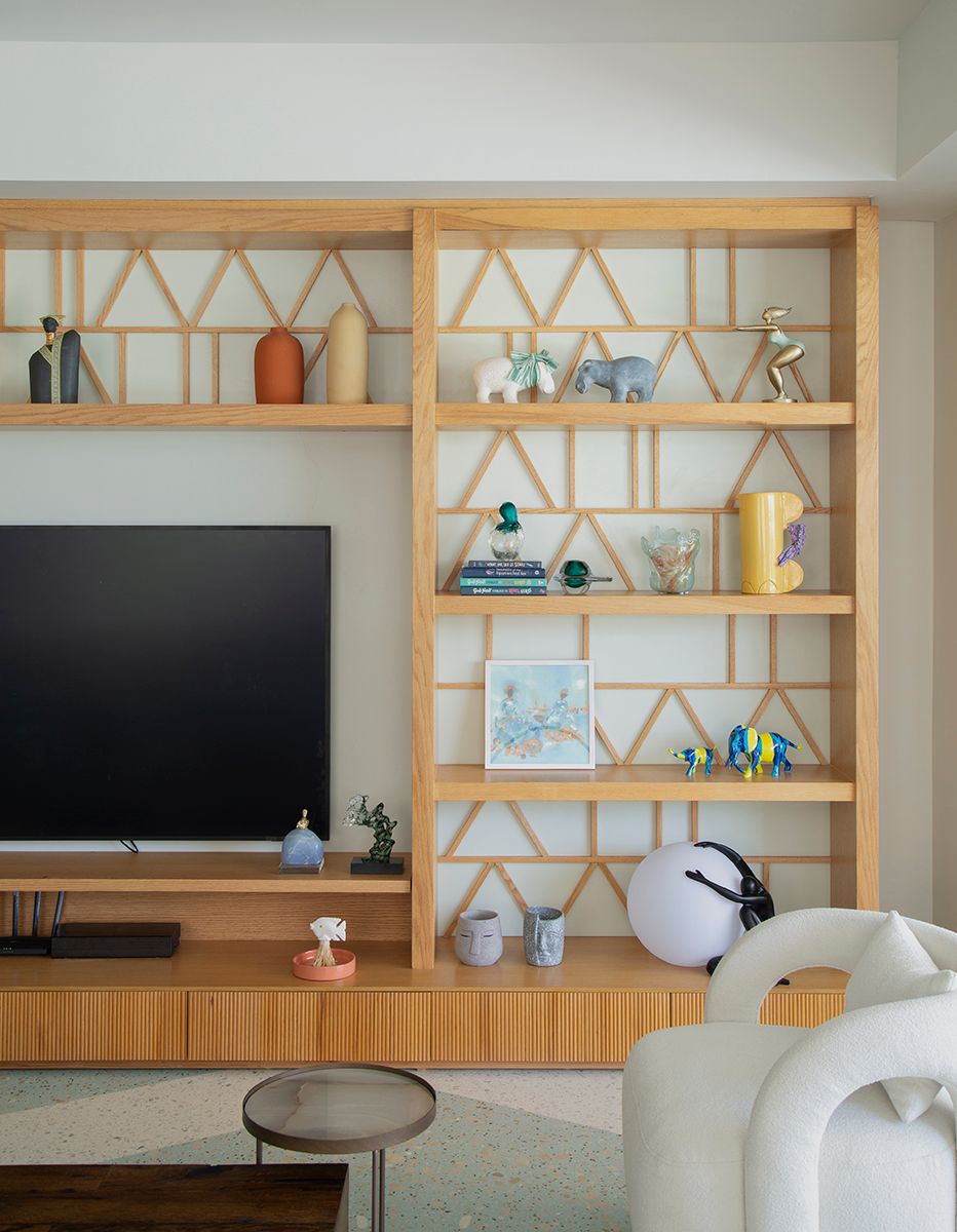 Contemporary living room entertainment unit with geometric wooden shelving displaying decorative objects.