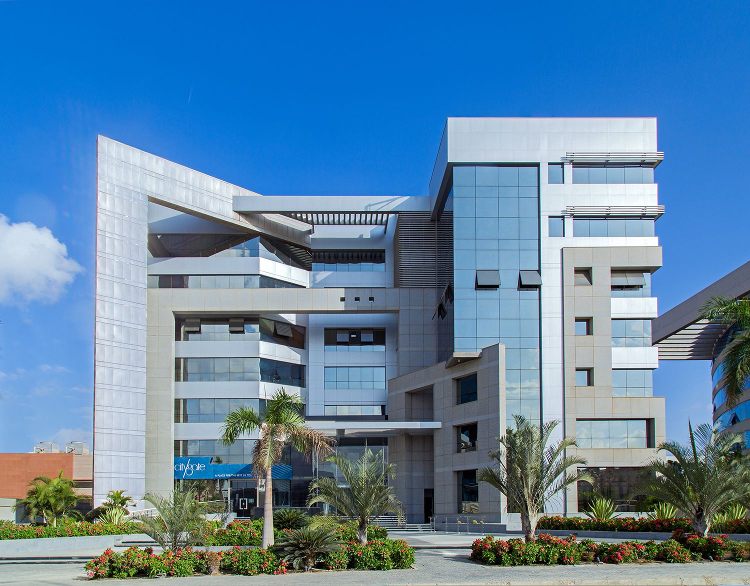 Modern geometric office building with glass facades and angular architecture under blue sky.