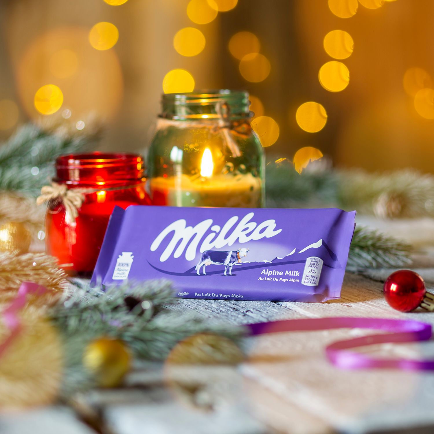 Milka chocolate bar with holiday decorations and candles creating a festive atmosphere.