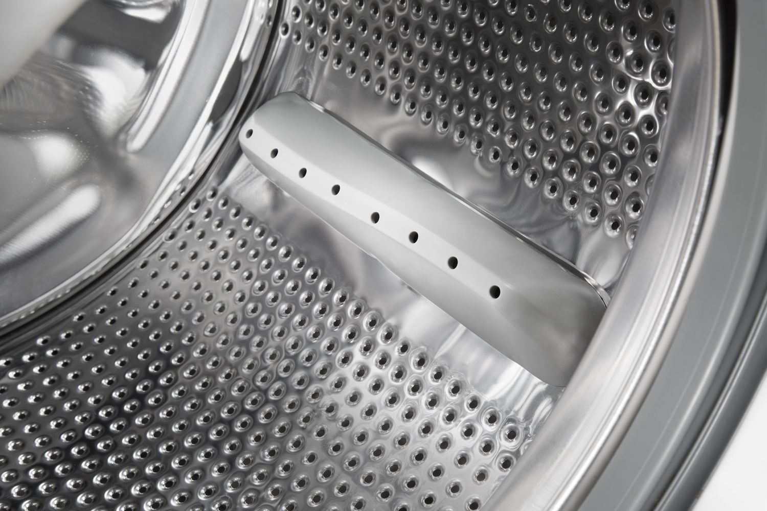 Close-up of stainless steel washing machine drum interior showing perforated pattern.