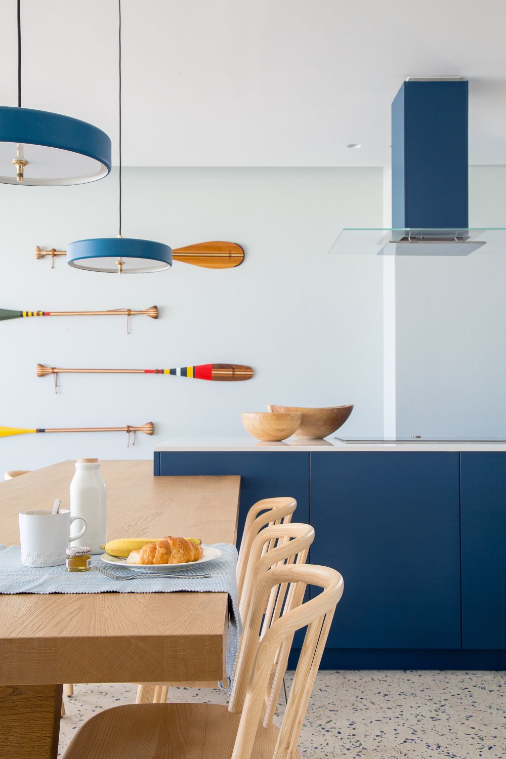 Nautical-themed dining space with decorative oars and navy blue cabinetry.