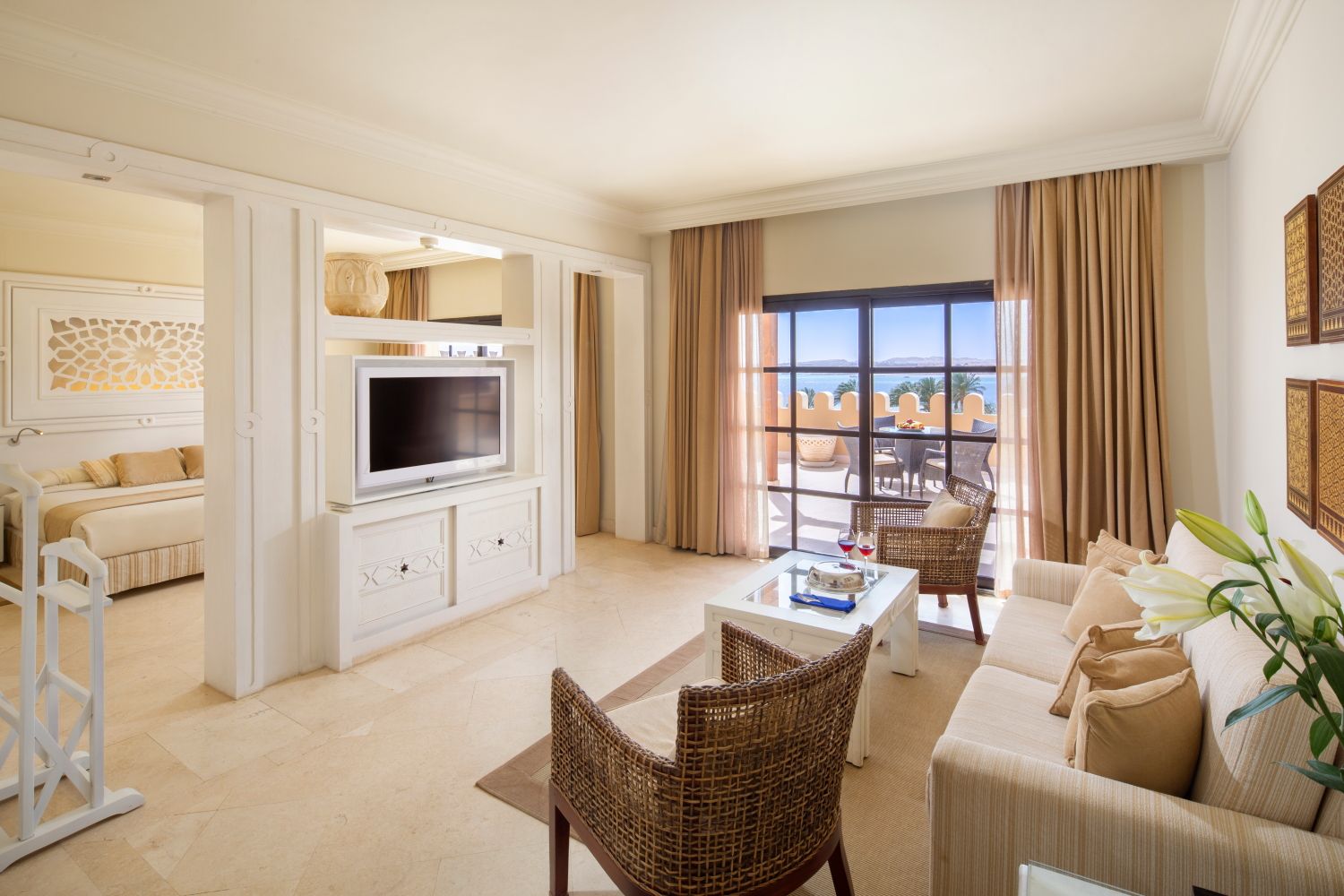 Bright coastal suite living room with neutral decor, built-in entertainment center and ocean view balcony.