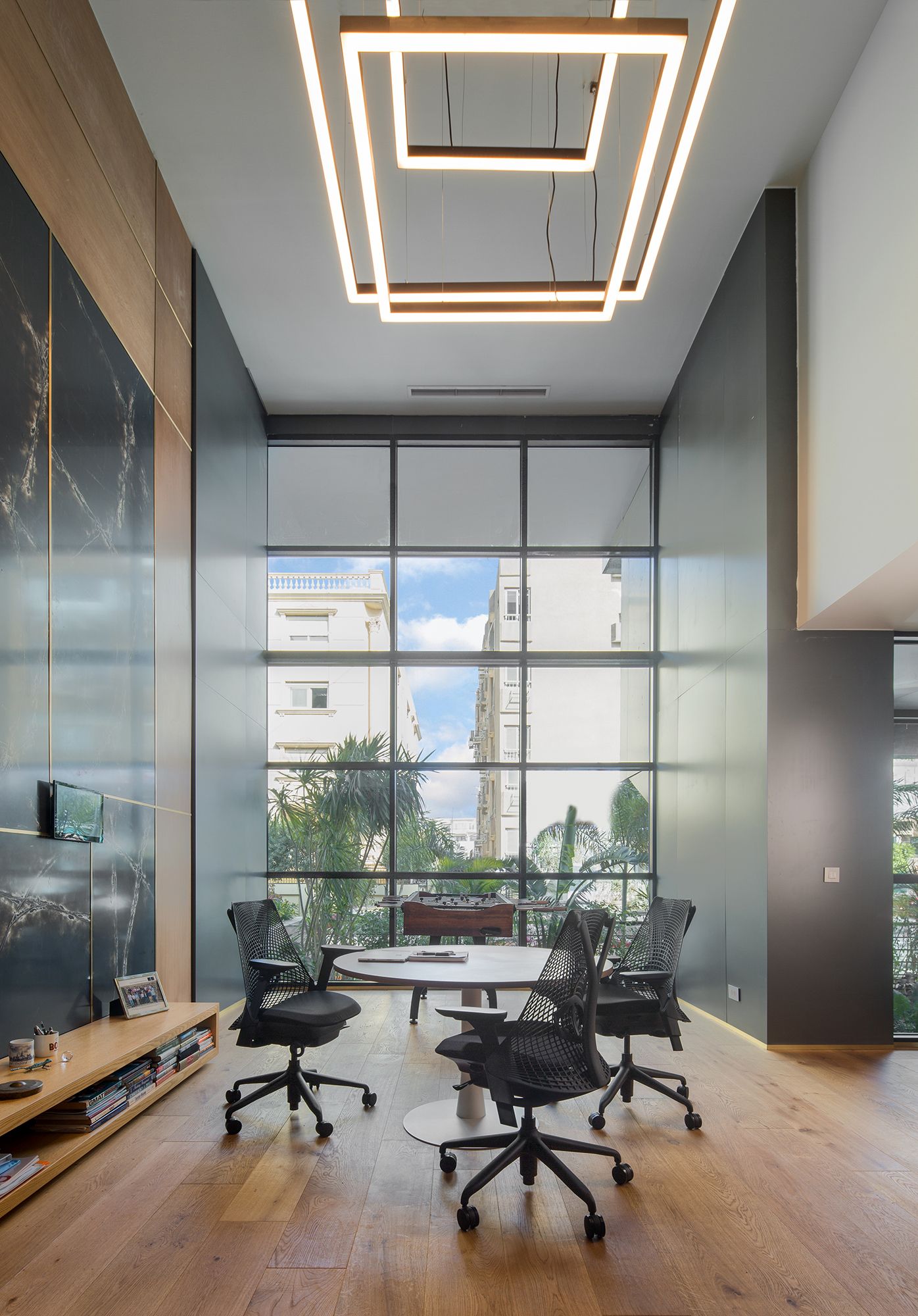 Contemporary meeting space with geometric ceiling lights and floor-to-ceiling windows.