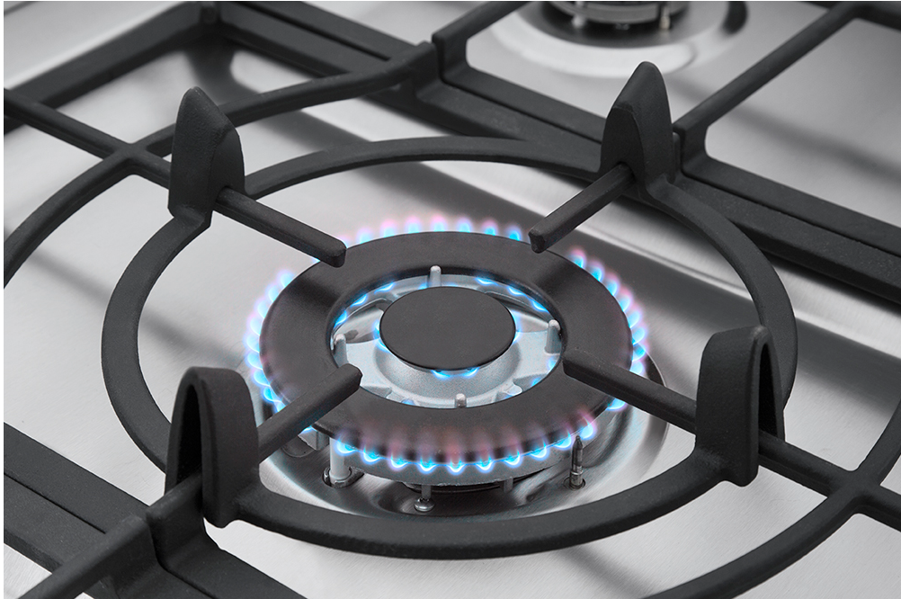 Close-up of a lit gas stove burner showing blue flame ring on white surface.