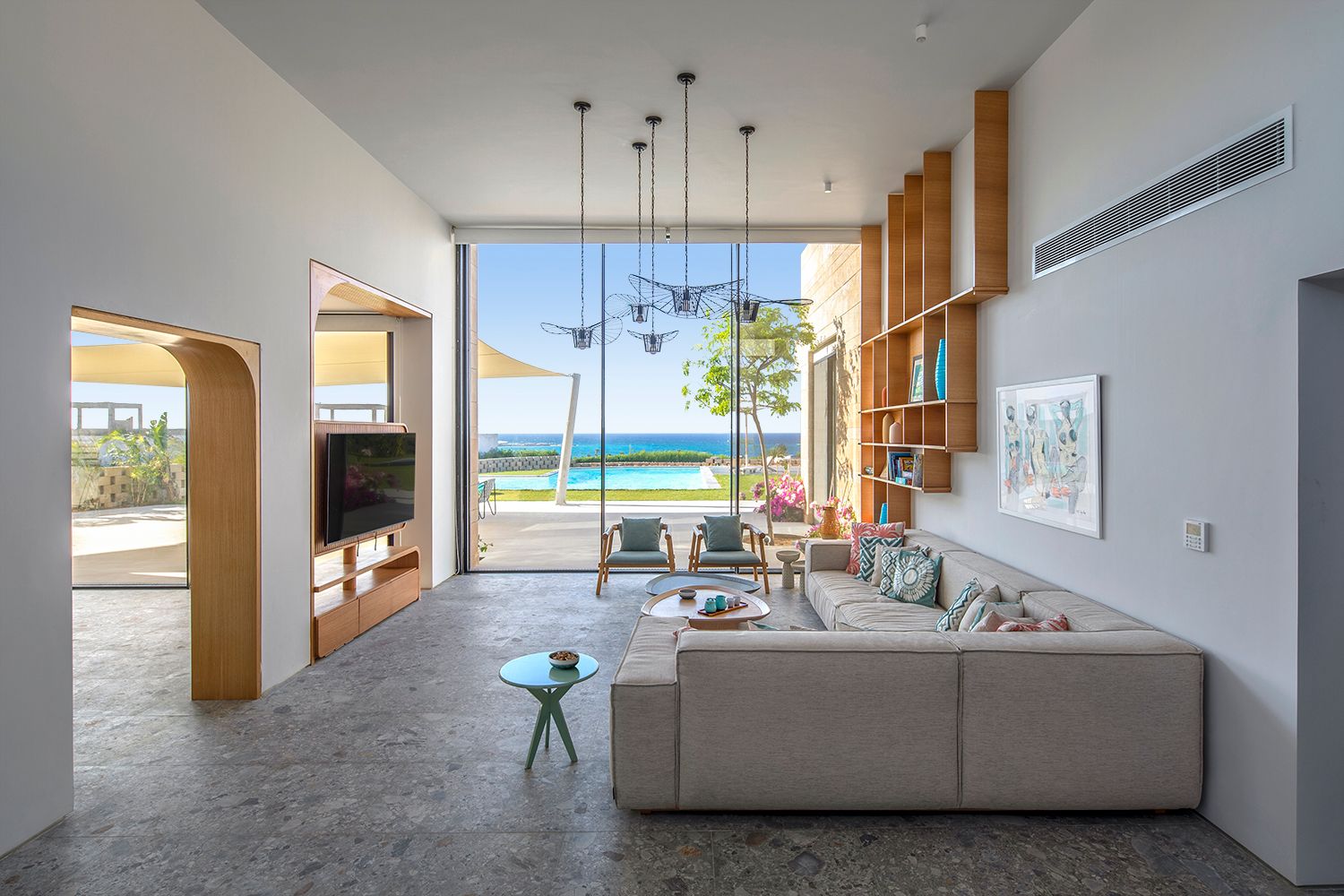 Coastal living room with high ceilings and ocean view through floor-to-ceiling windows.