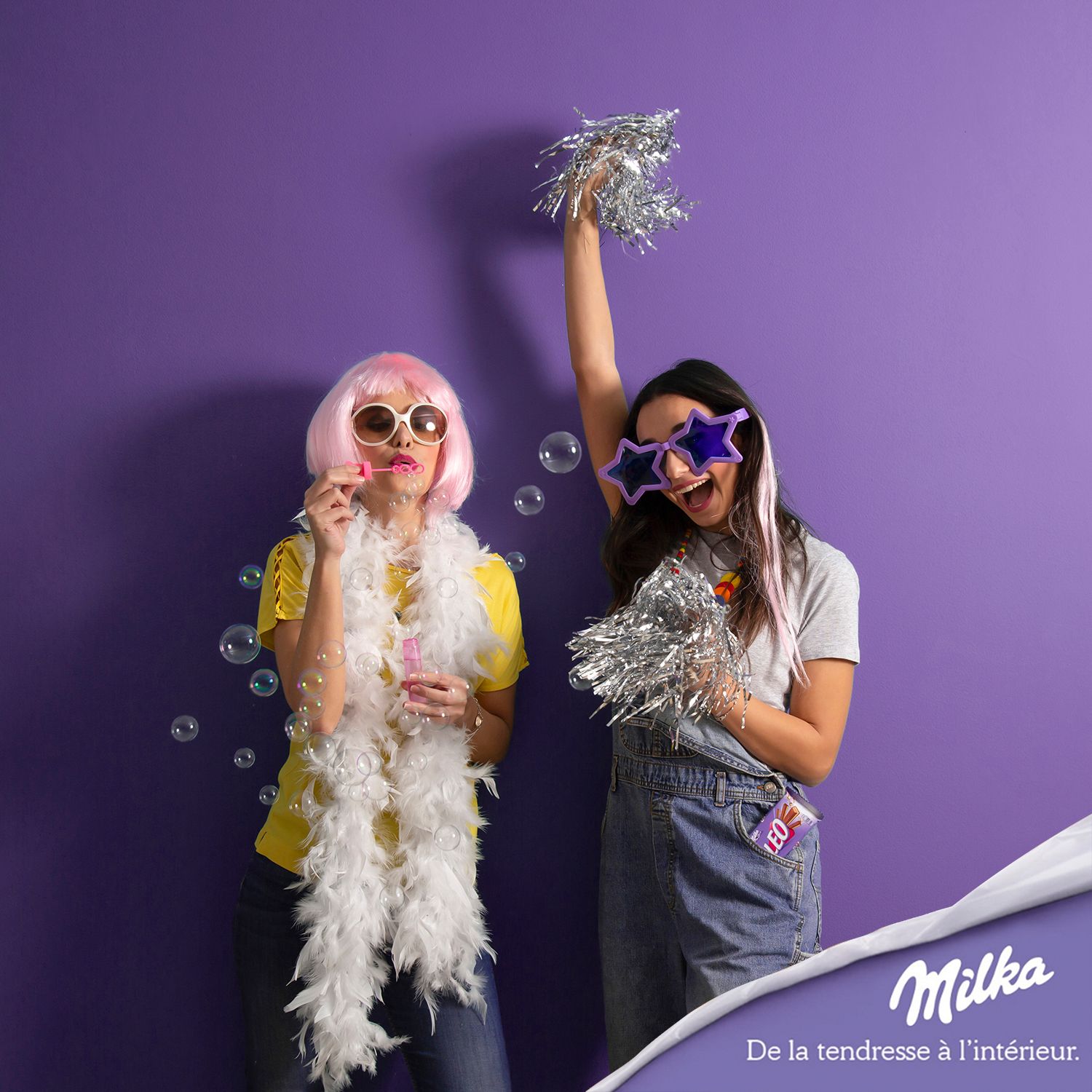 Playful scene against purple wall with silver decorations and party accessories. Milka ad
