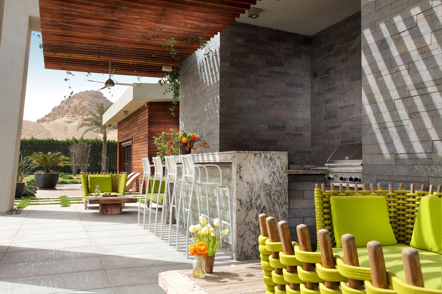 Modern patio with lime green chairs and stone columns overlooking mountain landscape.