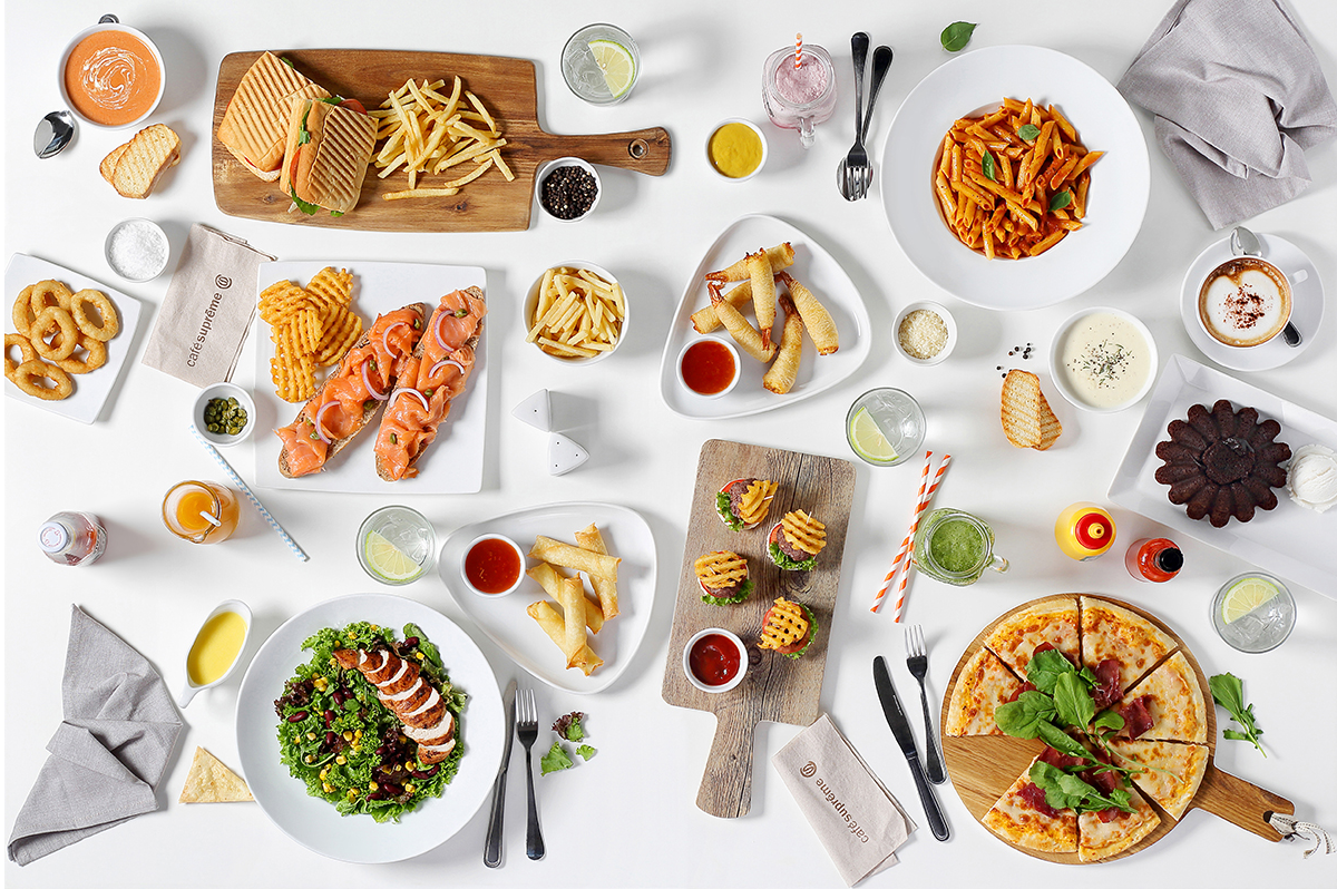 Overhead view of extensive brunch spread with various dishes and appetizers on white table.