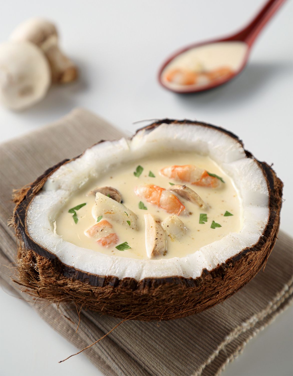 Creamy seafood soup served in fresh coconut shell with garnish.