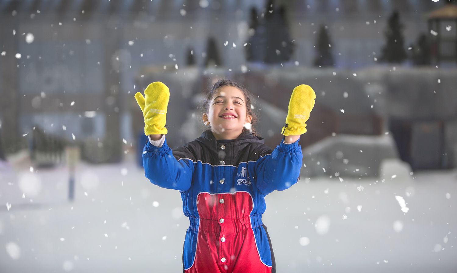 Winter scene with yellow mittens raised in joy as snow falls.