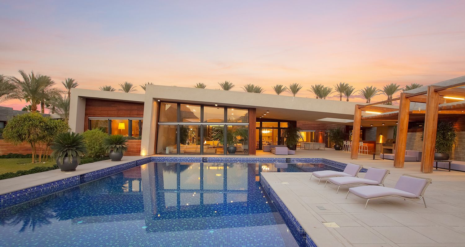 Luxury villa with infinity pool and palm trees at sunset.