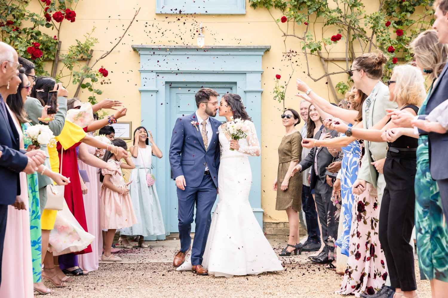 Wedding guests toss colorful flower petals outside a church in a celebratory exit line tradition.