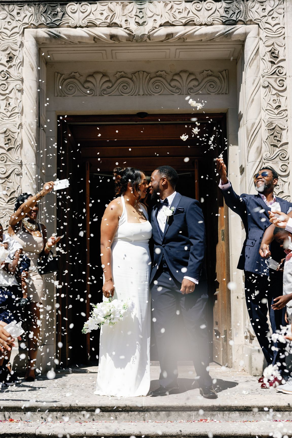 Shelana and Peter celebrating with confetti at their London wedding, captured by Oisin Studios
