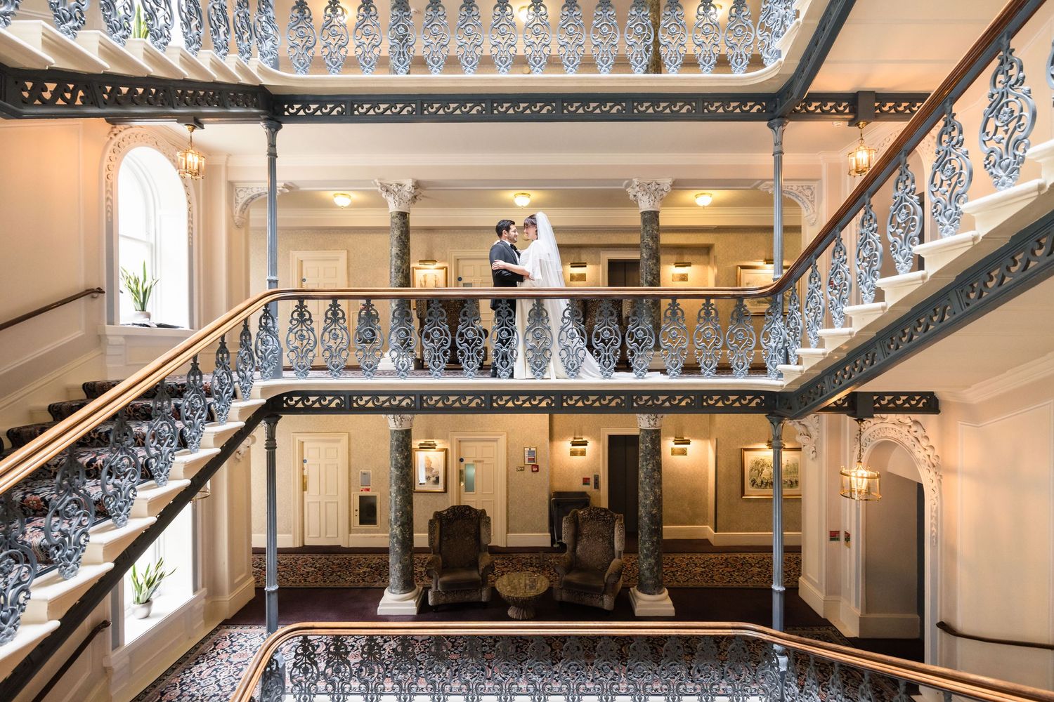 Elegant ornate staircase with decorative wrought iron railings in a grand historic building interior.