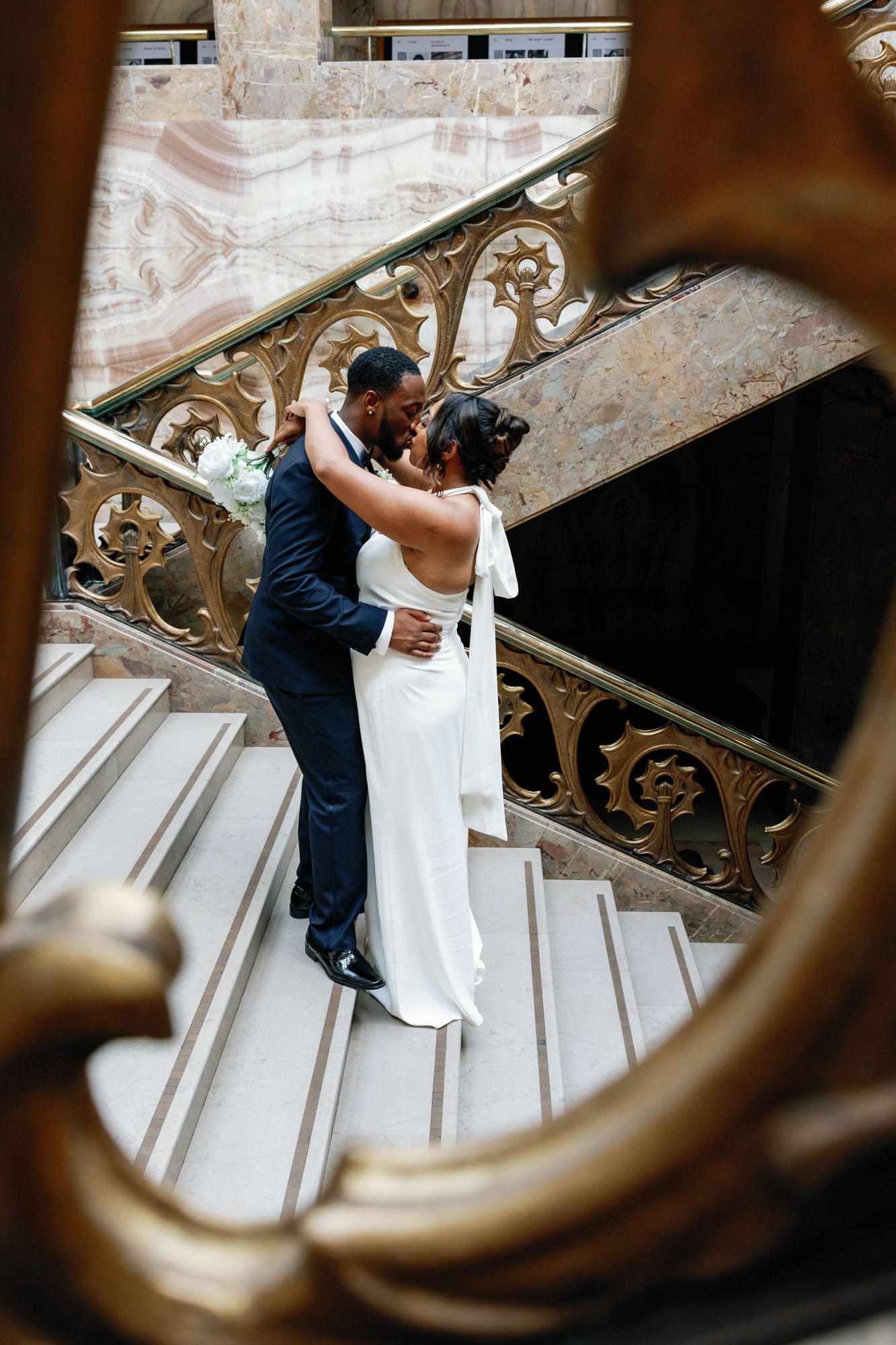 Shelana and Peter’s couple portrait sharing a kiss on the stairs at their London wedding, captured by Oisin Studios