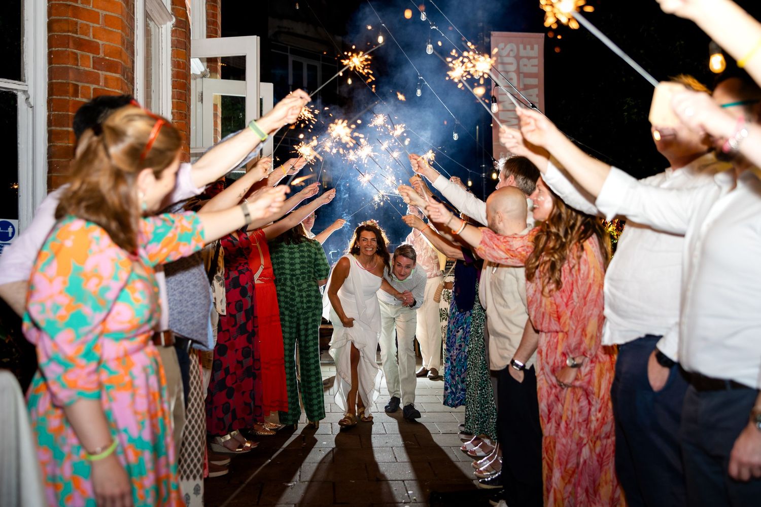 Wedding guests dance and celebrate with sparklers during an evening reception on the dance floor.