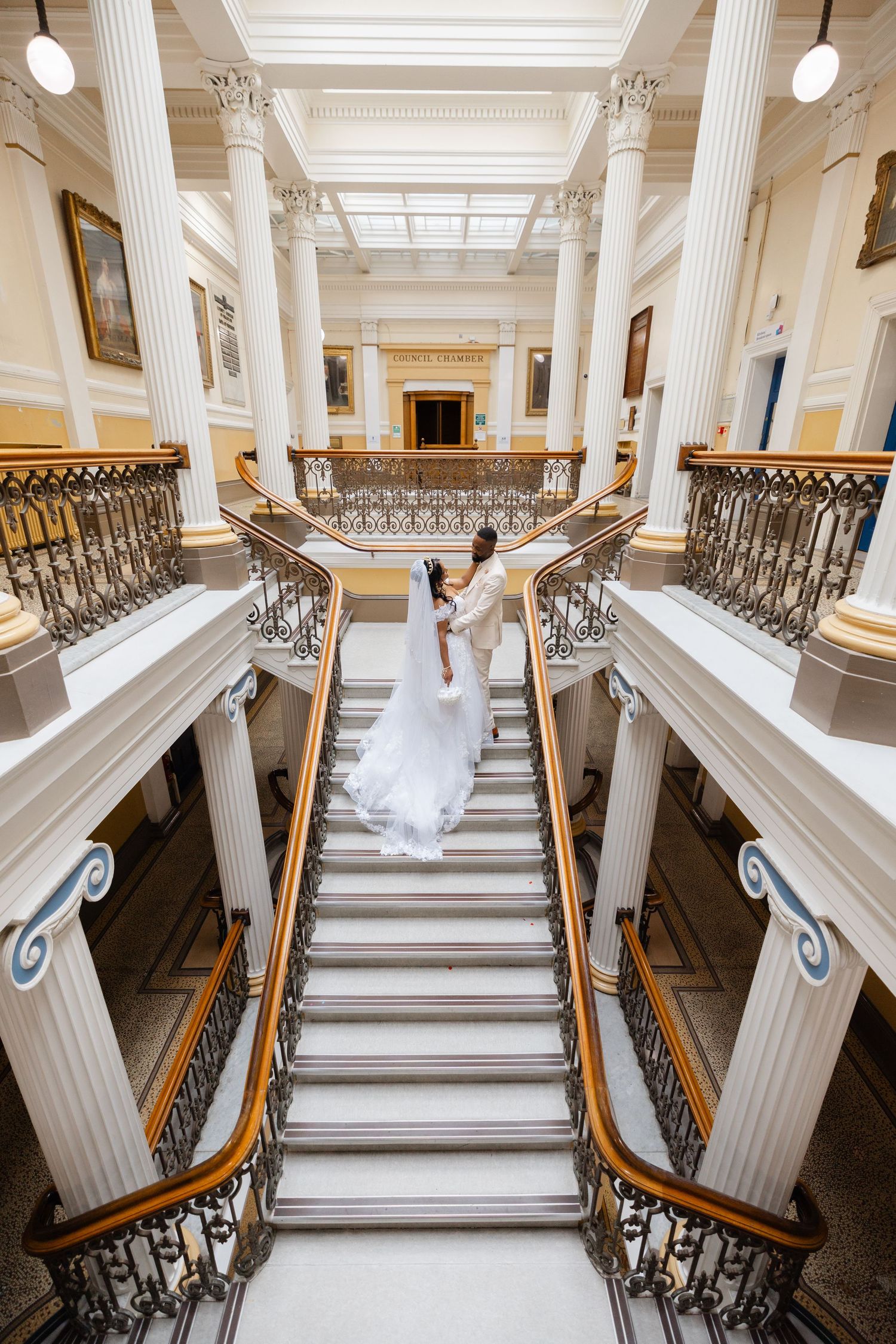 Elegant grand staircase in historic mansion with ornate white columns and decorative metal railings.