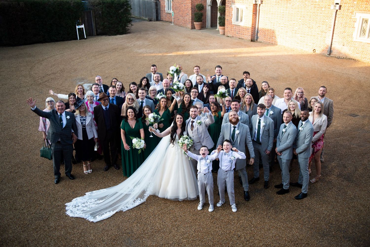 Aerial sequence of wedding party groups posing outdoors at dusk for formal photographs on church grounds.
