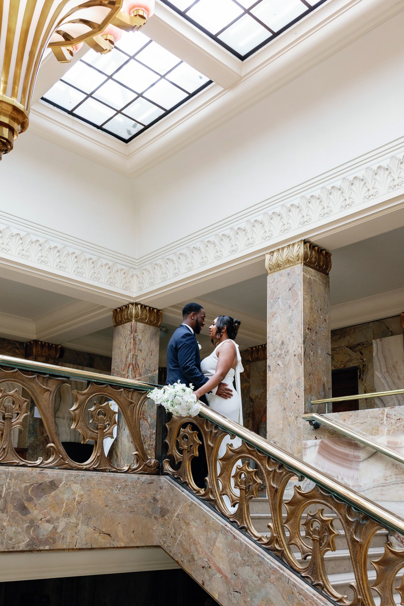 Shelana and Peter’s wide couple portrait on the stairs at their London wedding, captured by Oisin Studios
