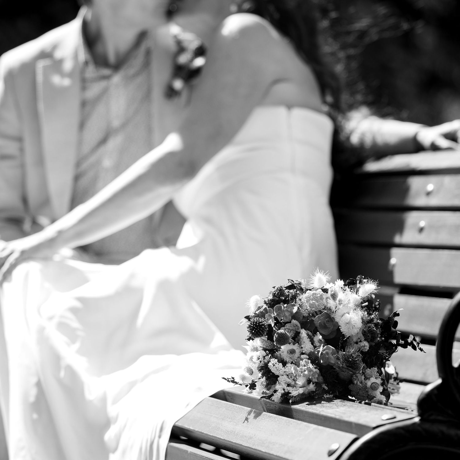 Two hands sign papers and documents on a wooden desk with an elegant floral bouquet visible in the background.