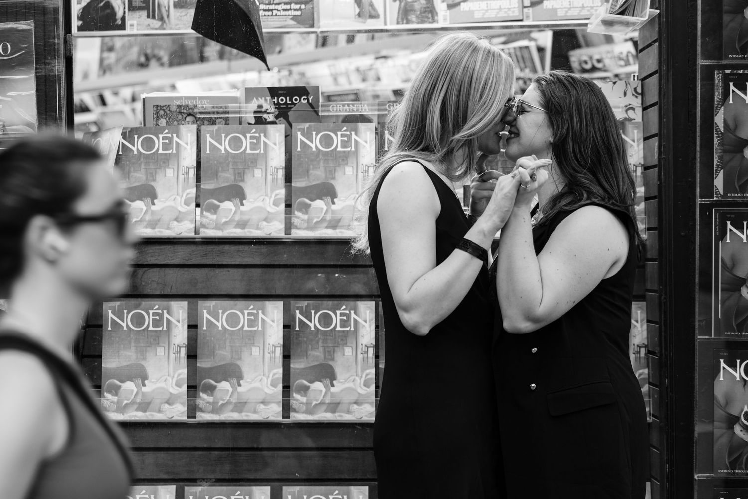 Black and white photo of two women sharing an intimate moment outside a bookstore.
