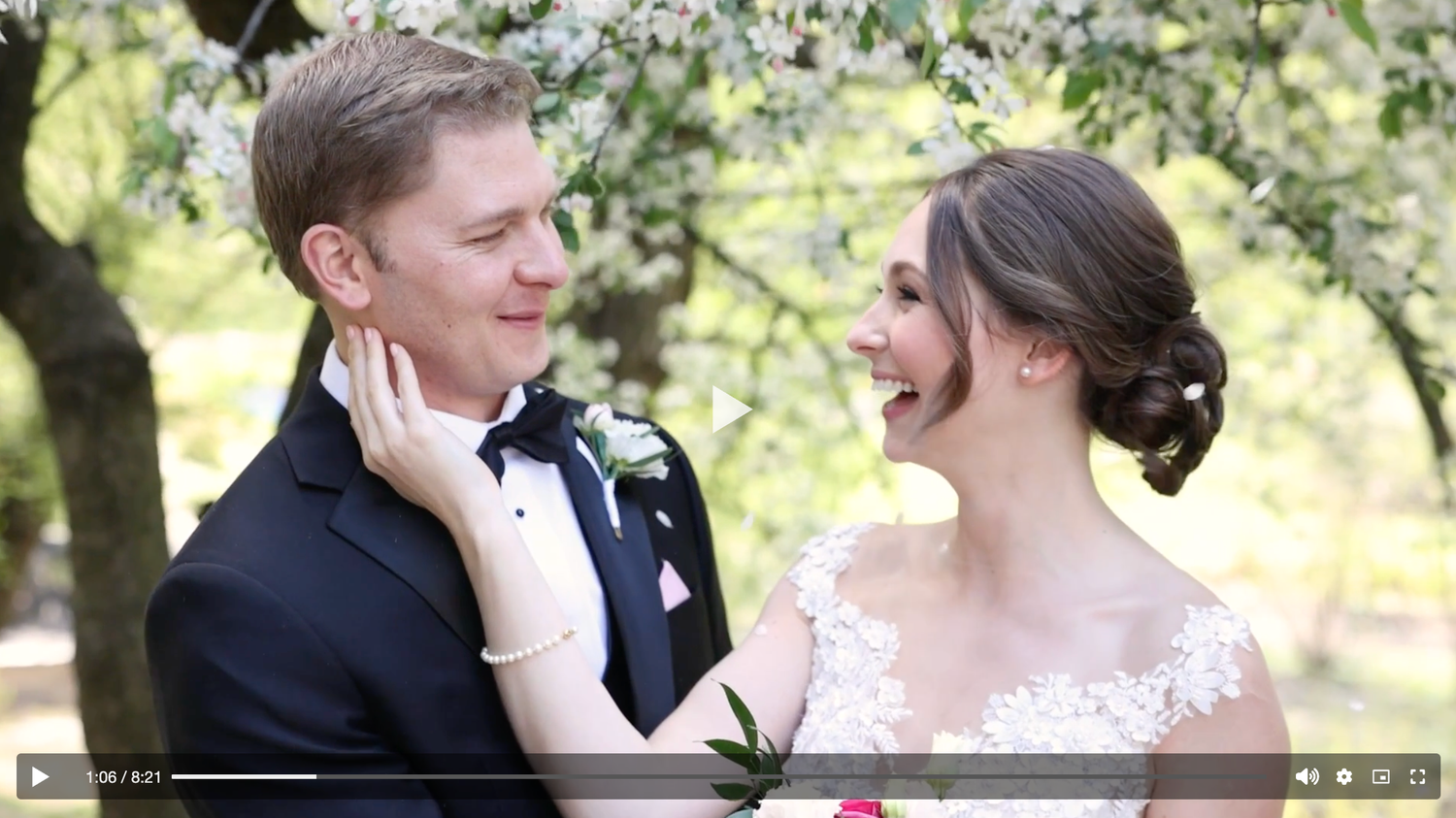 Bride and groom sharing a joyful moment under blooming spring trees in a wedding video.