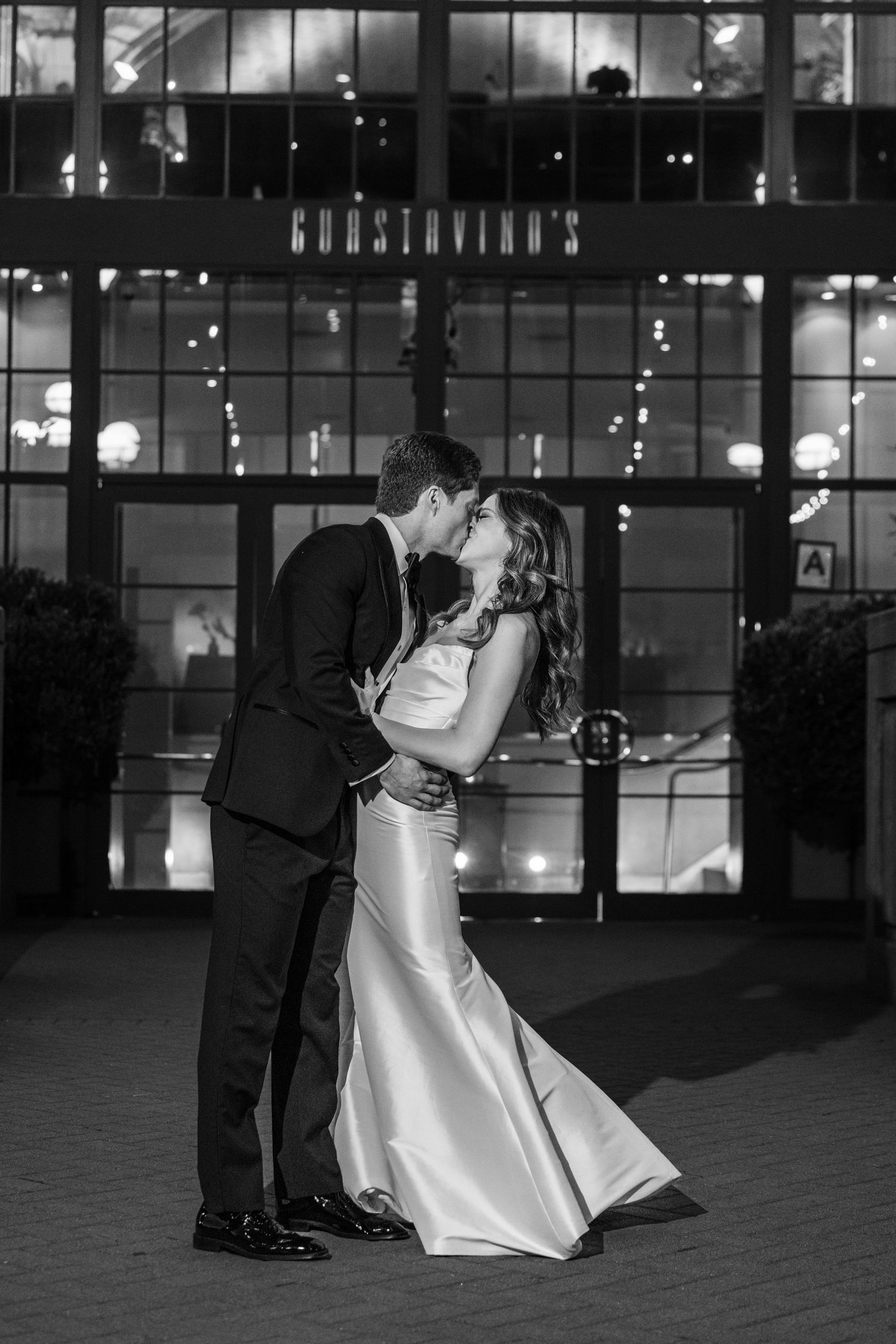 Black and white portrait of newlyweds sharing a romantic kiss outside Guastavino's at night.