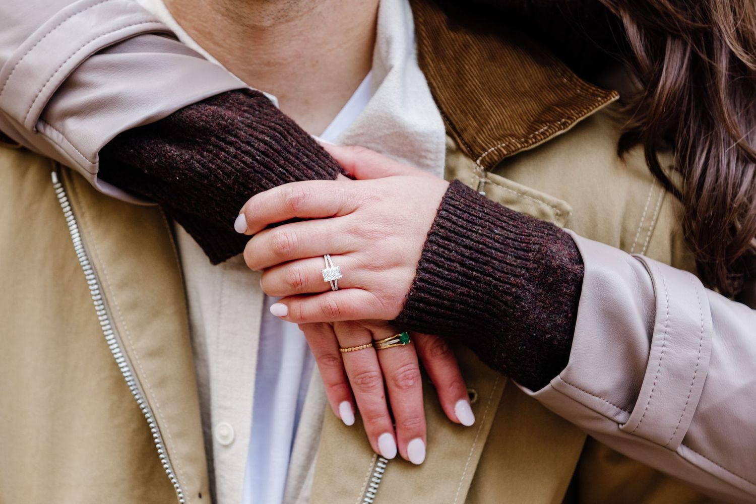 Close-up of an engagement ring on a woman's hand resting on her partner's chest.