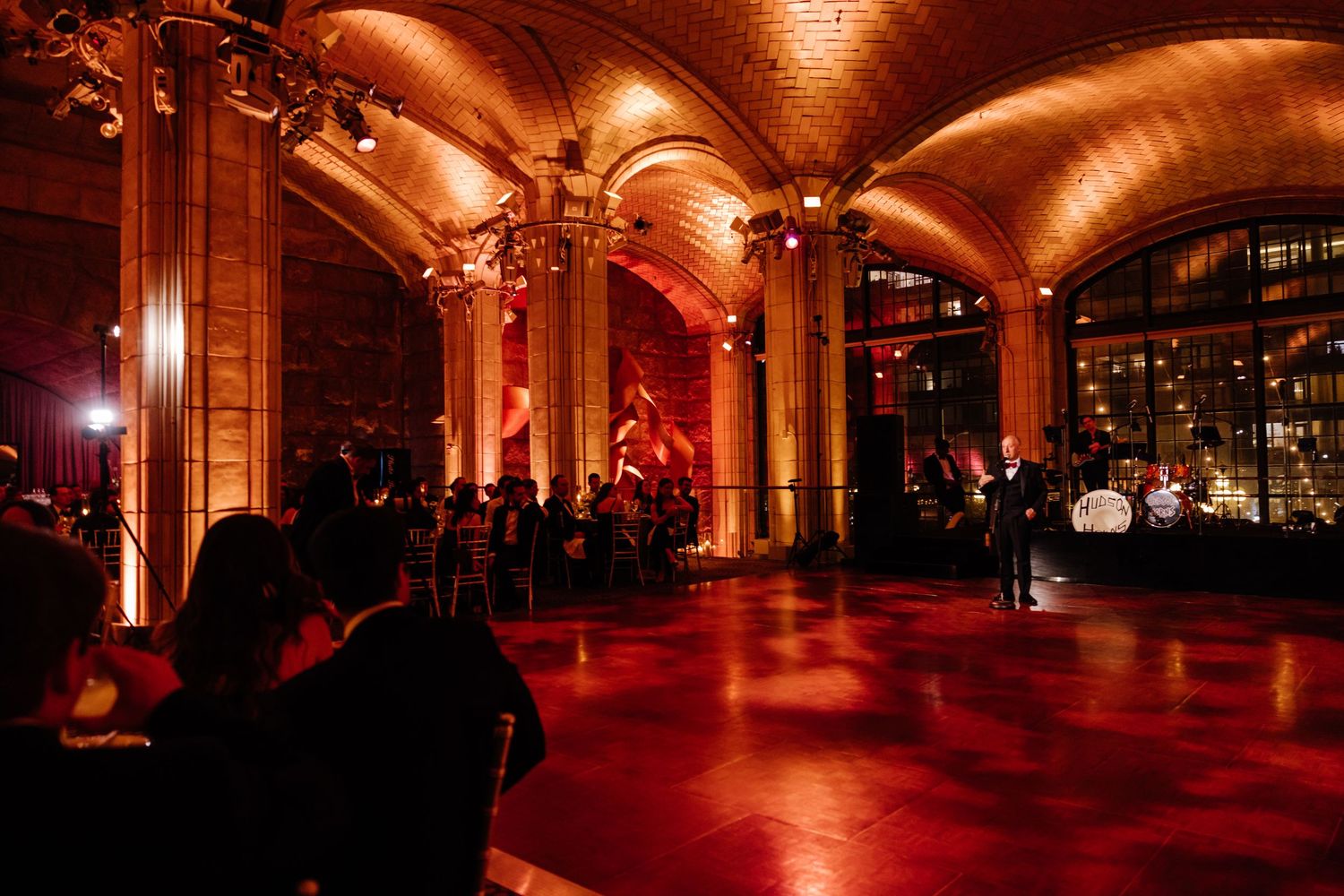 Grand wedding reception venue with arched ceilings bathed in warm red ambient lighting.