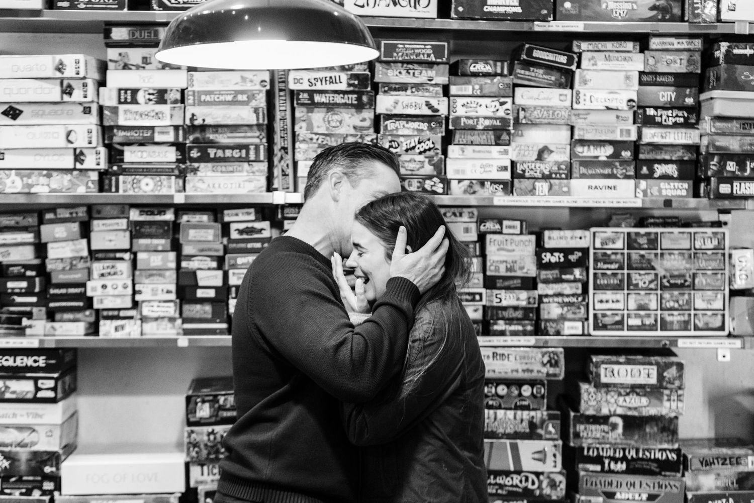 Newly engaged couple sharing a kiss surrounded by board games at The Uncommons.